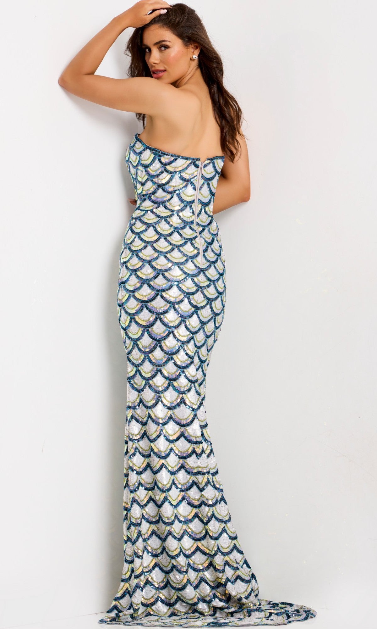 A woman stands with her back to the camera, wearing the Jovani 49260 long prom dress—a floor-length off-white strapless gown, sequin beaded in a scalloped pattern with a zippered back.